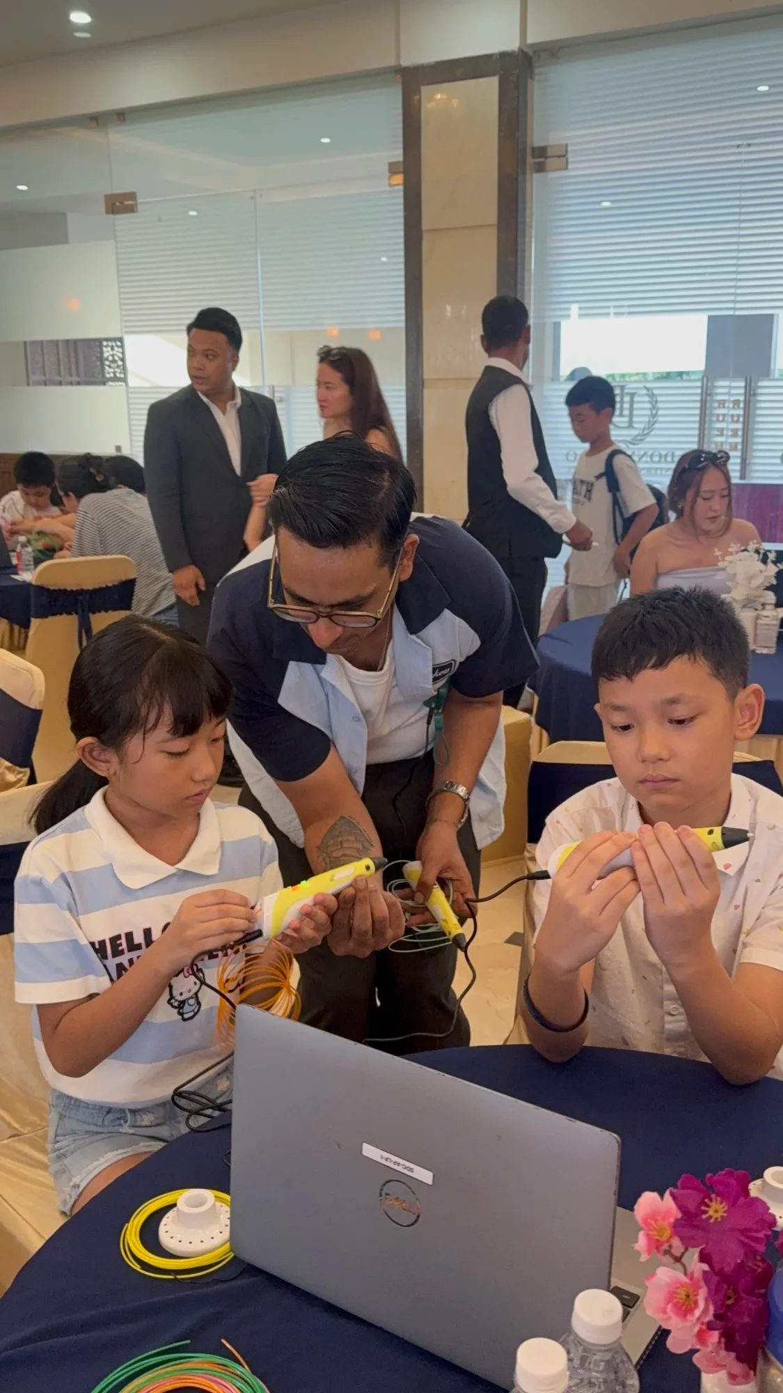 An NEbots instructor guiding two children through a hands-on build at a robotics workshop in Itanagar